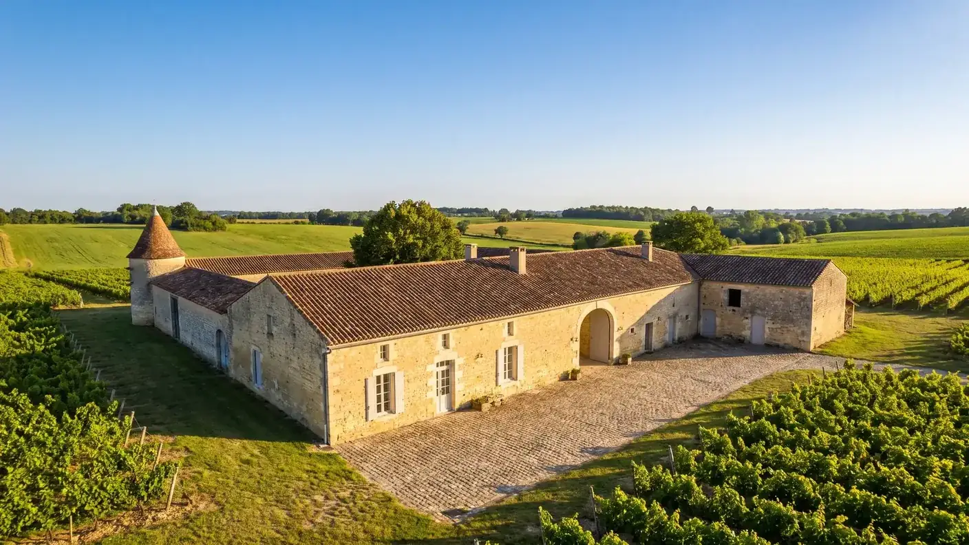 Una granja tradicional de la Charente cerca de Birac, una larga construcción de piedra color miel con tejado de tejas y una gran verja