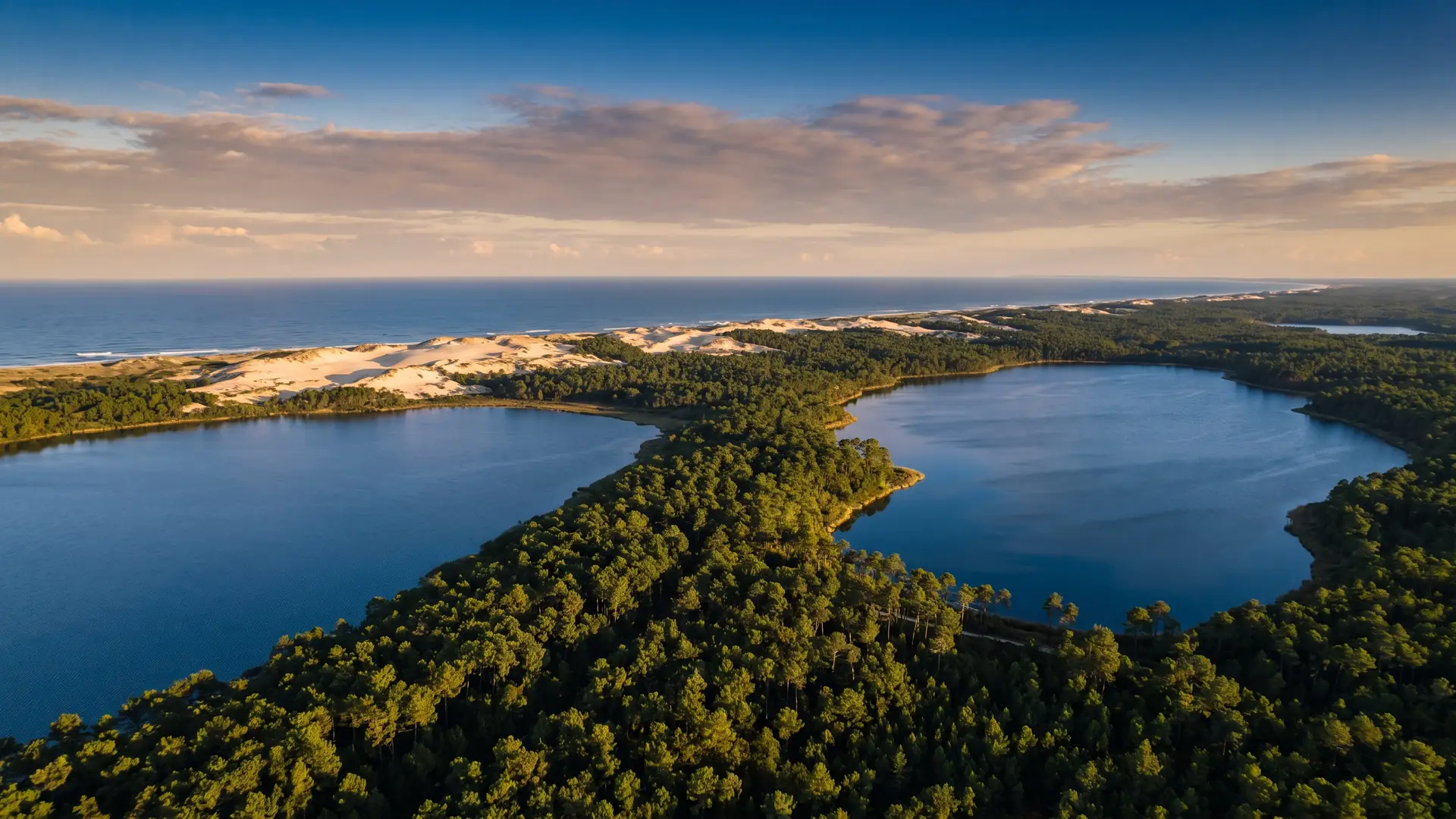 Dos inmensos lagos azules separados por una franja de bosque de pinos, la línea de dunas y el océano a lo lejos