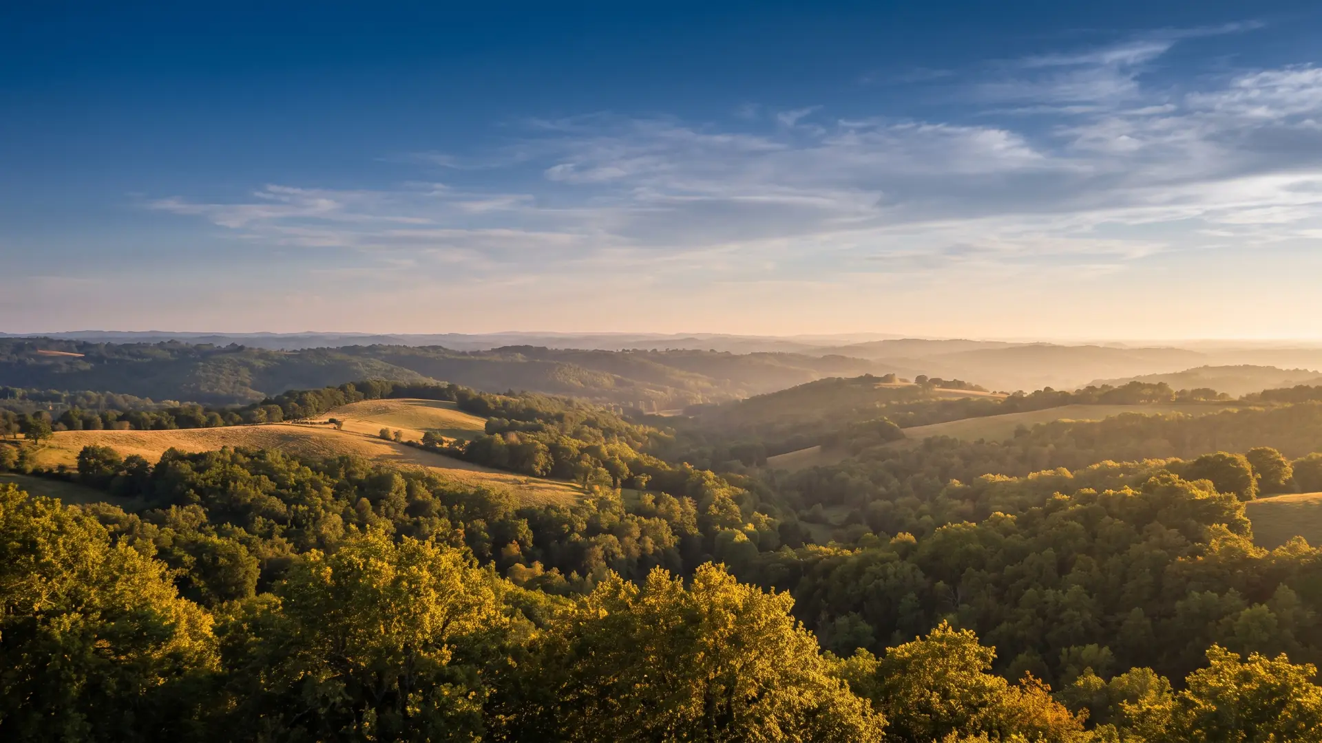 A panoramic view of the wooded hills of Guyenne near Villeréal, bathed in golden light, around the Château de Fonrives campground