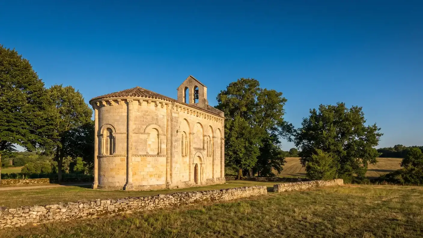 Una pequeña iglesia románica del siglo XII, construida en piedra caliza de color miel, situada en Gironda, con cabecera redondeada y campanario