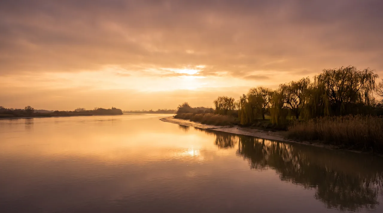 El Garona, tranquilo al atardecer, a lo largo de una orilla de sauces y juncos cerca de Cérons, con sus aguas resplandecientes