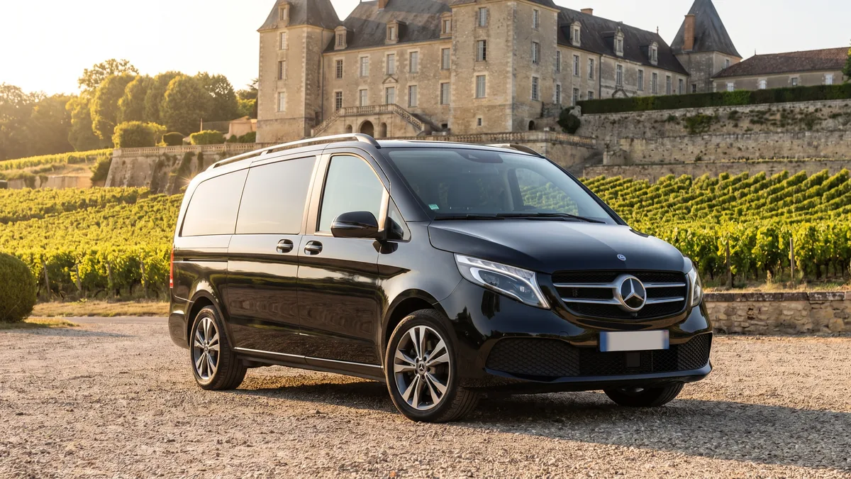 A black van with a driver parked in front of a wine chateau in the Bordeaux wine region