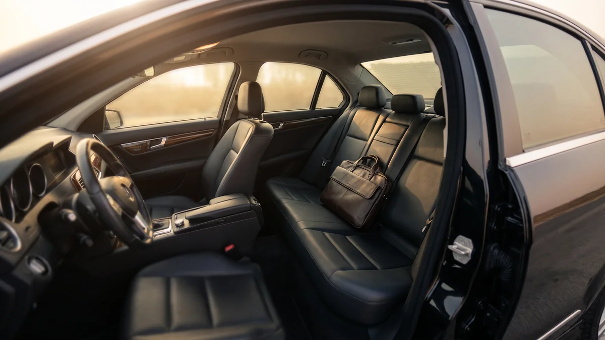 Interior trasero de cuero de una berlina con un maletín de trabajo colocado sobre el asiento trasero
