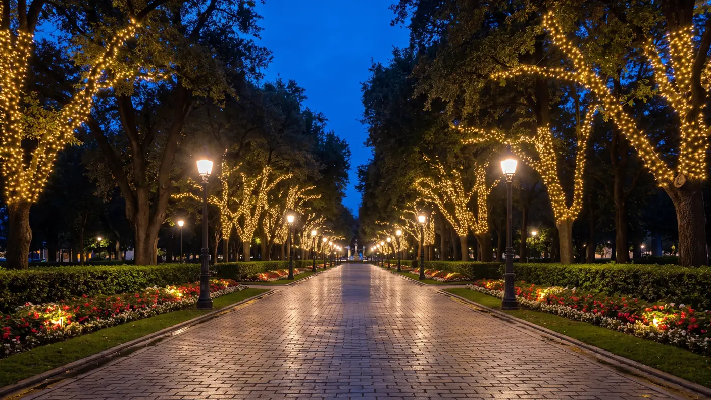 Avenida arbolada que se ilumina por la noche en un parque de atracciones