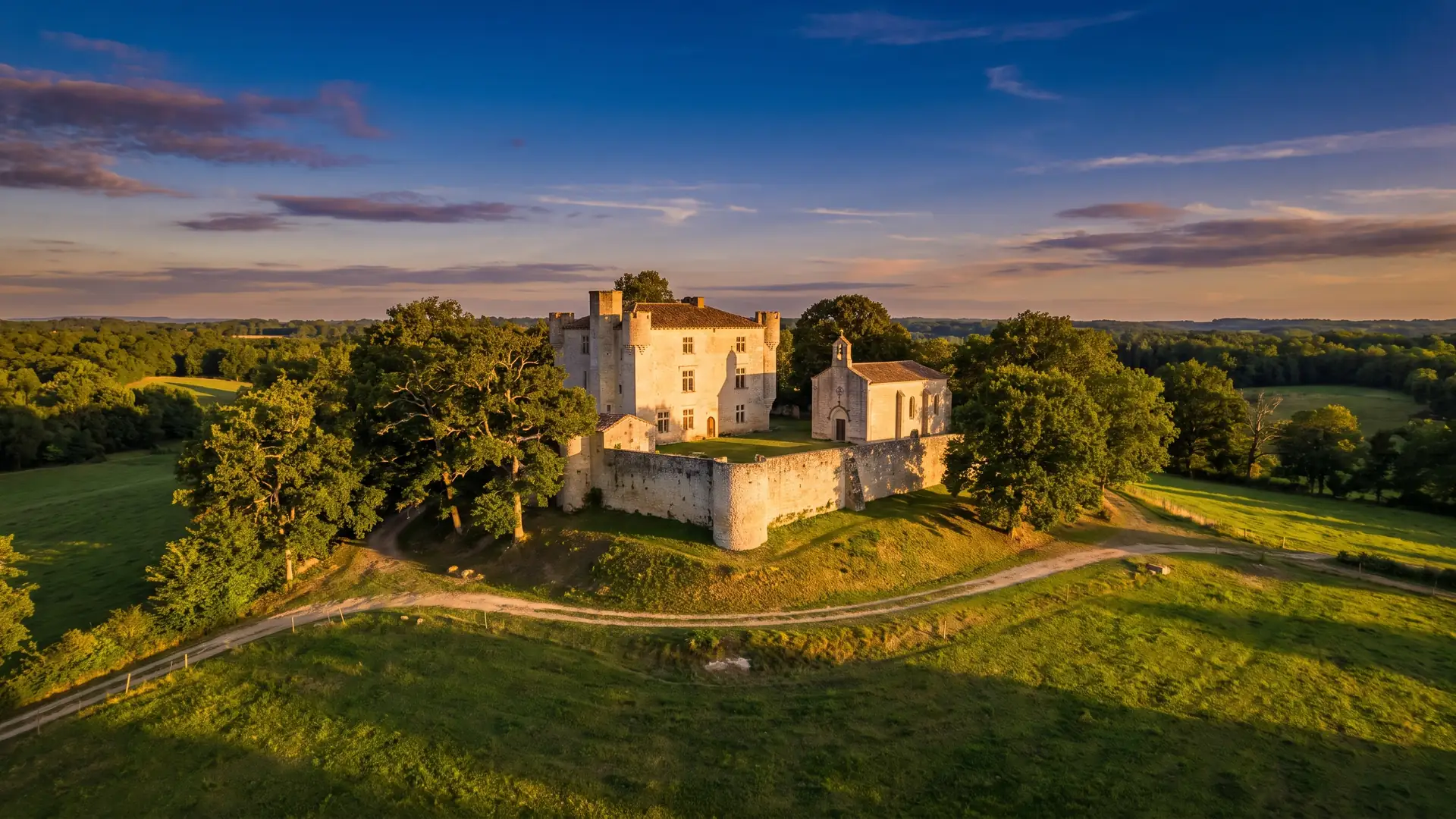 Una pequeña casa fortificada medieval de piedra situada en una loma, flanqueada por una capilla y una torre, en las Landas