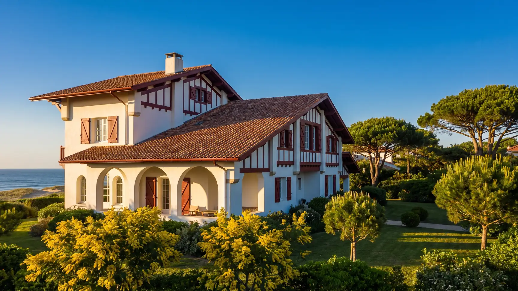 Una elegante villa vasco-landesa de la década de 1920, con paredes blancas y entramado de madera de color rojo oscuro, y un jardín de pinos