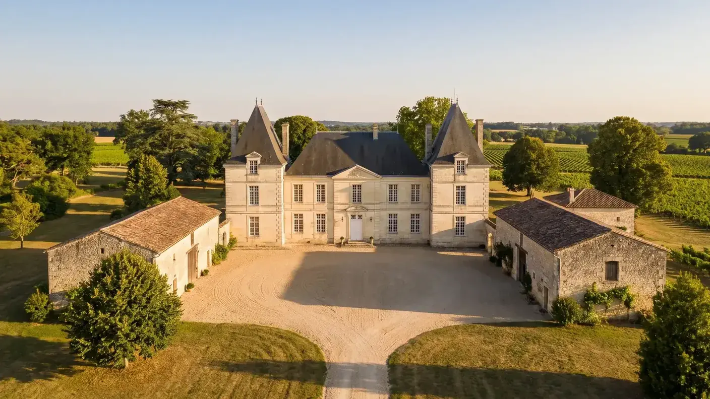 Casa vinícola de la Charente, construida en piedra tallada de color rubio, rodeada de viñedos y dependencias agrícolas, con tejados de pizarra