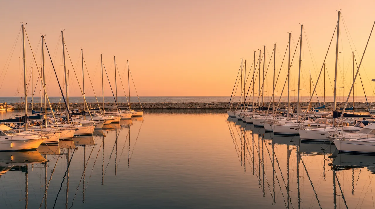 El puerto deportivo de Royan al atardecer, hileras de veleros blancos amarrados en aguas tranquilas, muelles claros a lo lejos