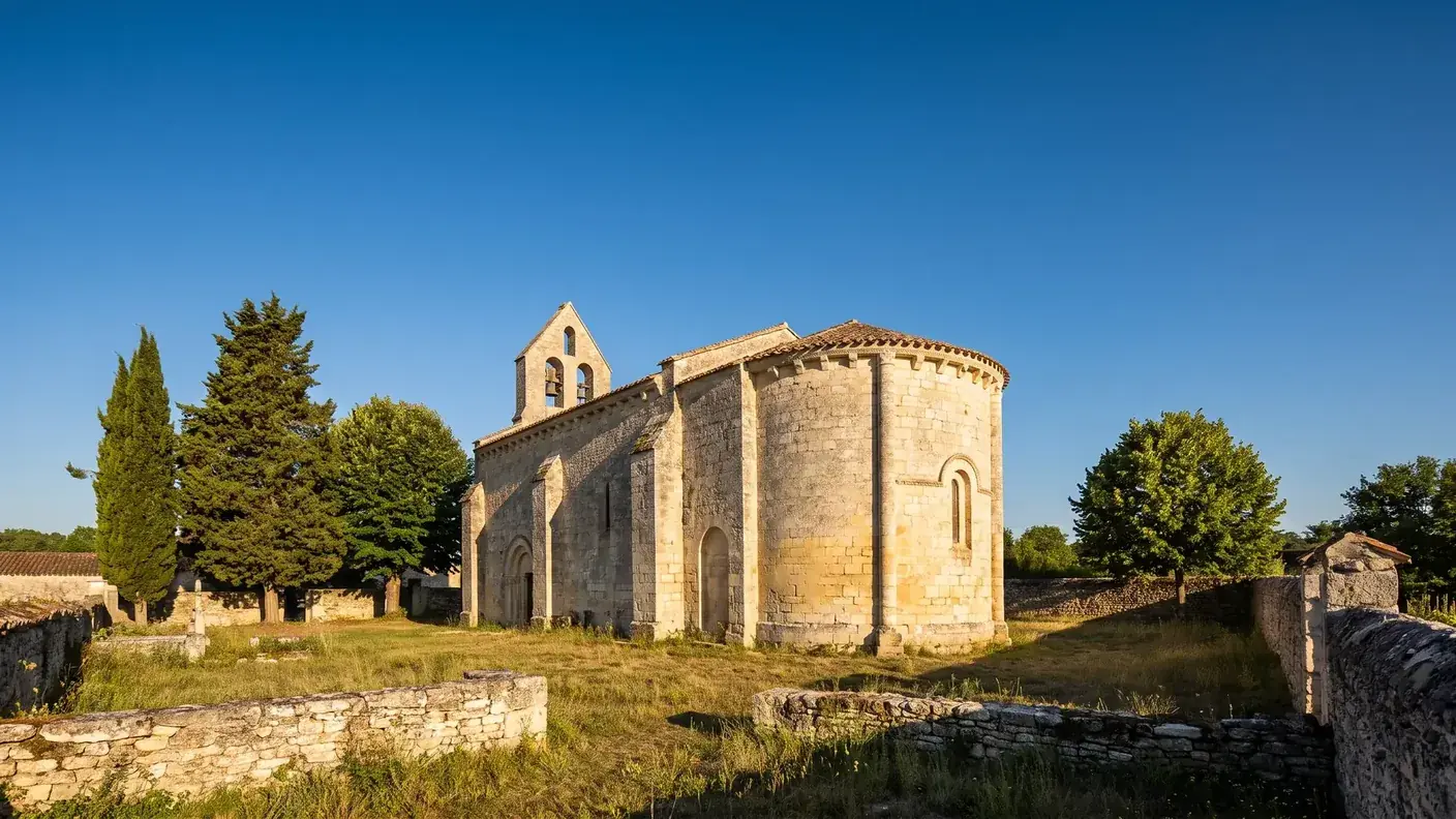 Una pequeña iglesia románica de la región de Saintonge, construida en piedra caliza clara, con ábside semicircular con modillones y campanario