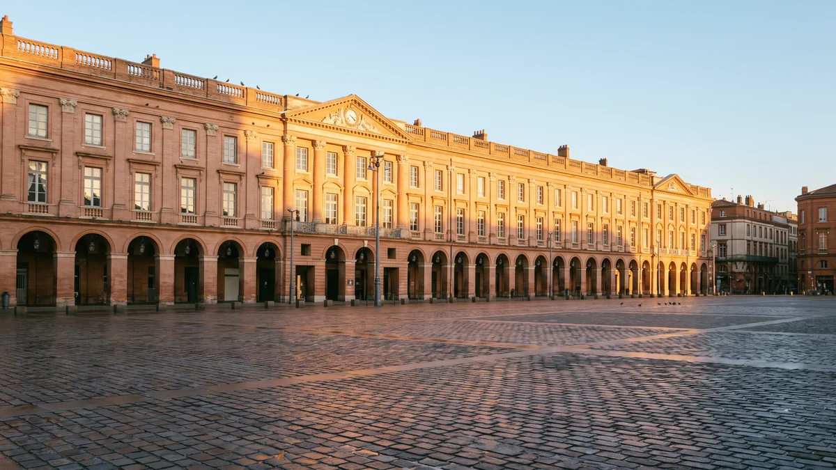 Executive transport service in a sedan in front of the pink brick buildings and the Garonne River in Toulouse